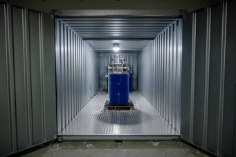 Um zu testen, wie robust und wie reproduzierbar der Funkfingerabdruck ist, haben die Forschenden ihre Technik in einem Container aufgebaut. Bewegungen des blauen Fasses lassen sich mit der Funkwellenüberwachung detektieren. Um zu testen, wie robust und wie reproduzierbar der Funkfingerabdruck ist, haben die Forschenden ihre Technik in einem Container aufgebaut. Bewegungen des blauen Fasses lassen sich mit der Funkwellenüberwachung detektieren.